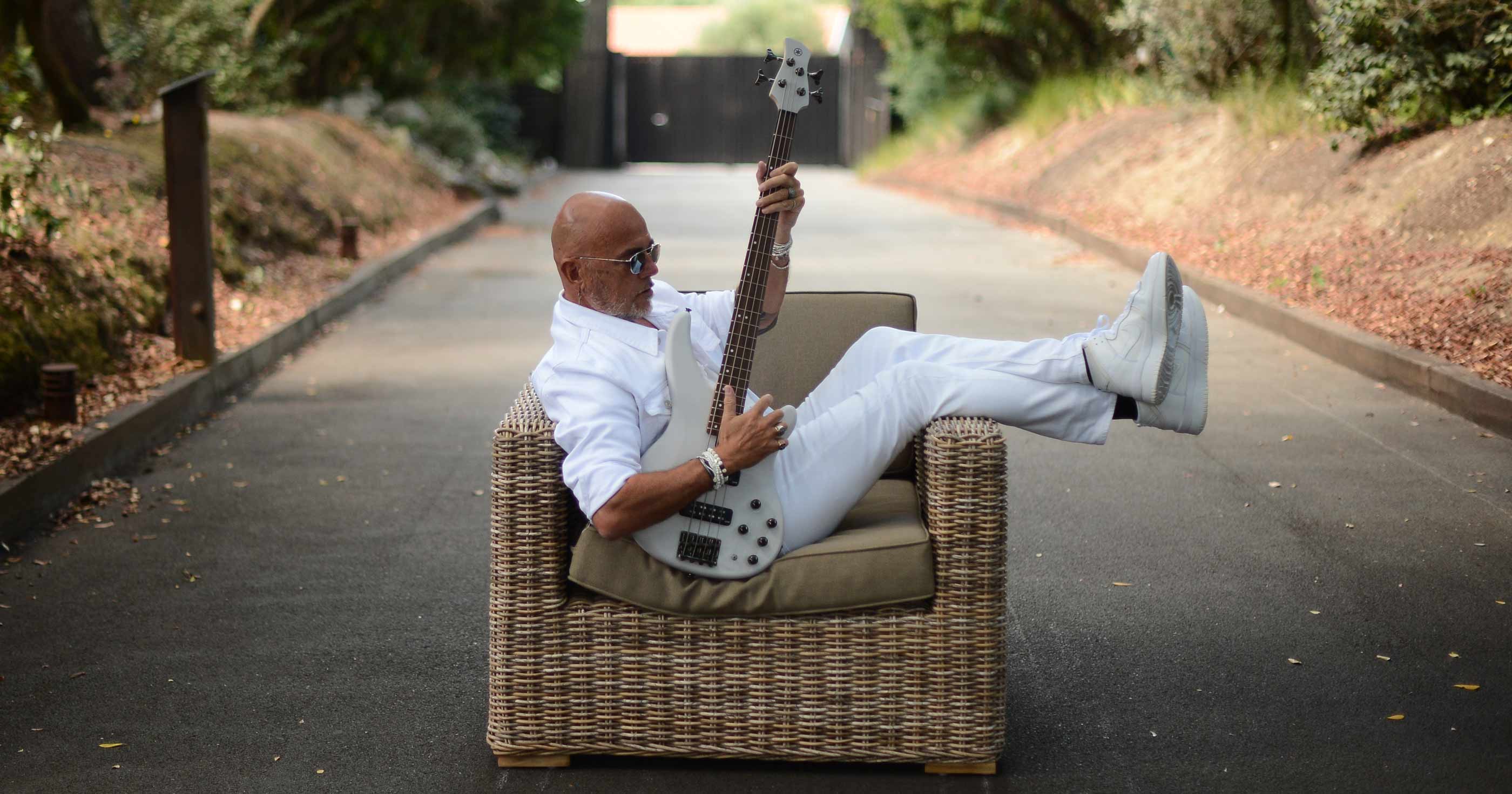 Pascal Obispo dans un fauteuil dans on jardin avec une guitare